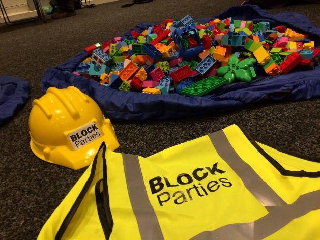 Block Parties florescent yellow jacket and hard hat, with a bag of Lego bricks