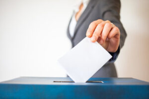 Image of a ballot box and vote being cast