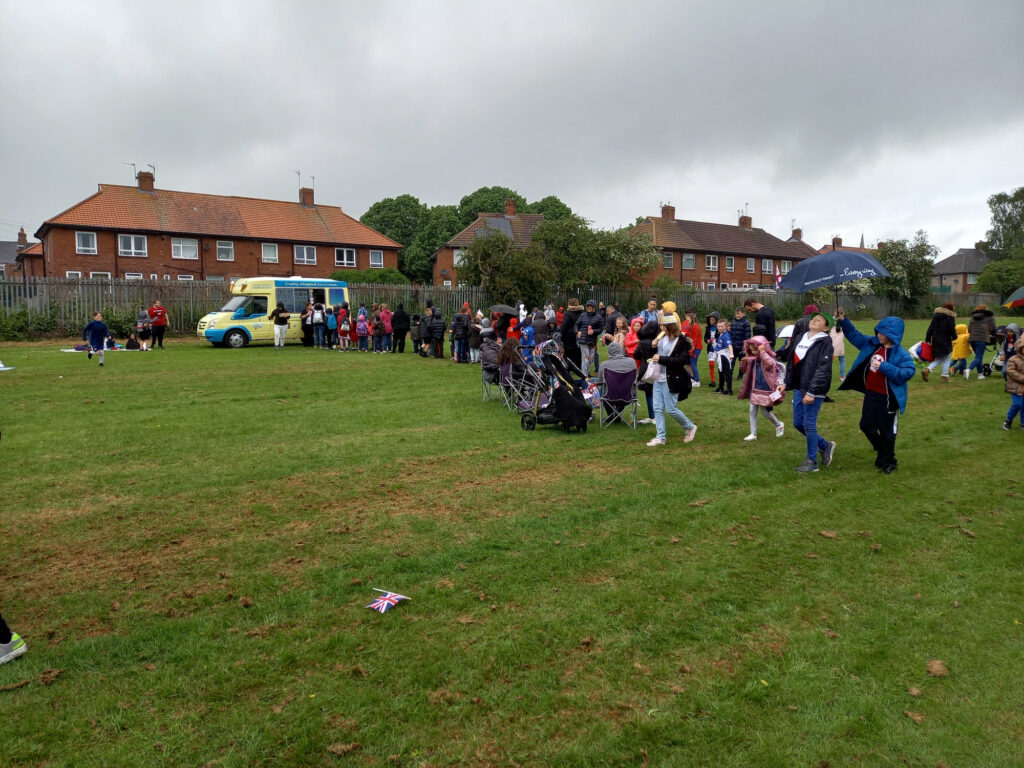 Children queuing for their free ice cream, despite the poor weather.