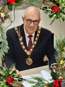 Mayor of Bishop Auckland, Councillor Mike Harker. Photograph with a Holly and Pinecone border.